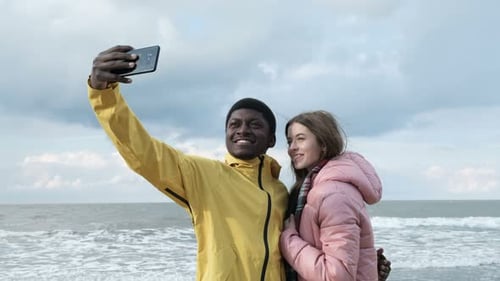 Cheerful Couple Taking Selfie on Overcast Beach Day