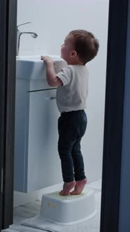 Boy Using Step Stool to Reach Bathroom Sink