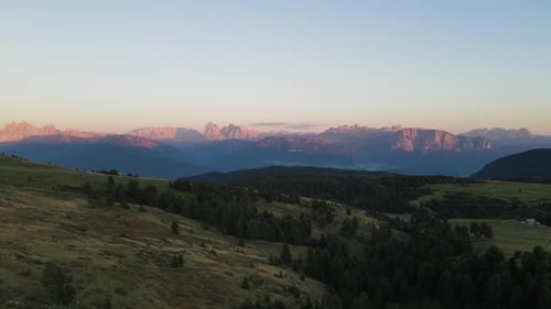 aerial drone shot of the alps while sunset with huts and farmland, beautiful nature. In the middle o