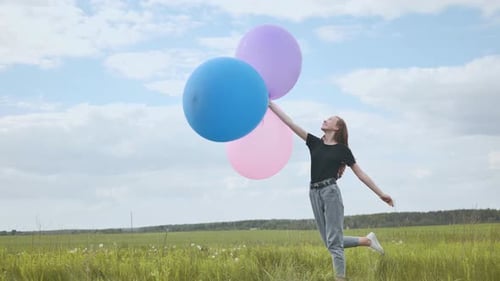 Happy Girl with Big Multicolored Balloons Posing on the Field