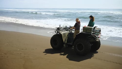 Travelers On Monster Quad Riding Over Sandy Beach On Ocean Coast Admiring Seagulls Flock
