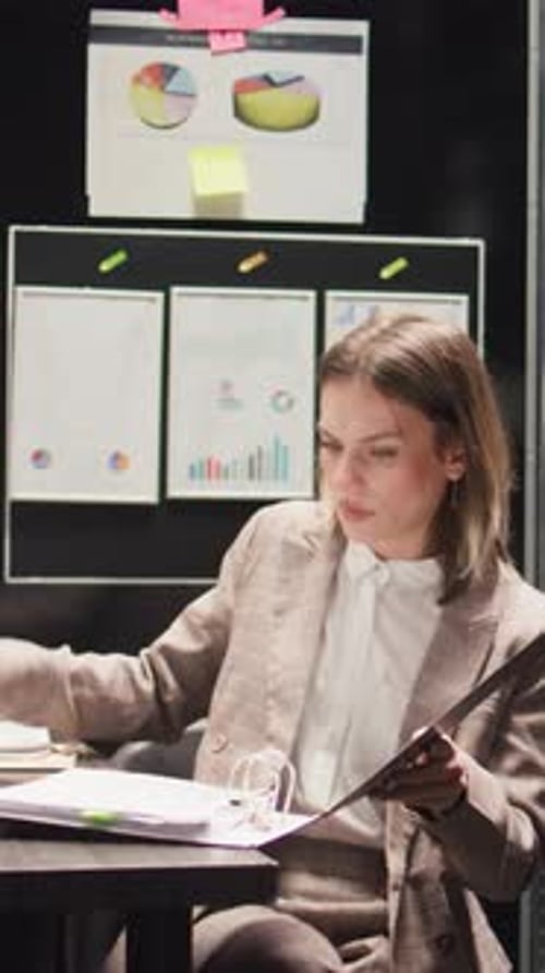 Woman Reviews Data and Paperwork in Office