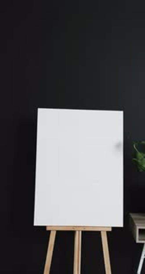 Vertical video of white canvas sign on wooden easel with copy space on black background