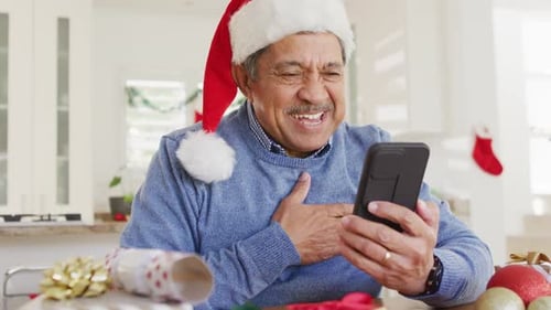 Man in Santa Hat Talks on Phone at Christmas