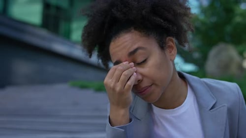 Tired Woman Rubbing Eyes Outside Office Building