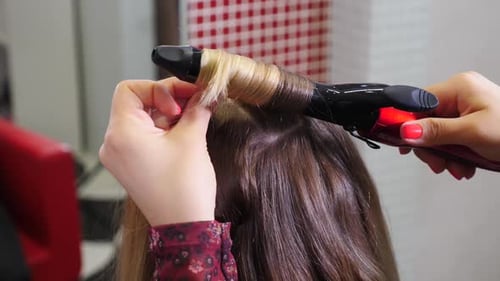 Hairdresser Curls Blonde Hair with Curling Iron