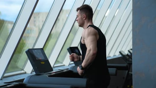 Young man running on the treadmill in the fitness studio