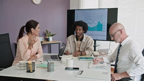 Three Colleagues of Marketing Department at Table in Modern Office