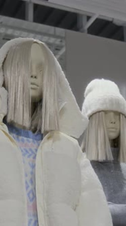 Vertical of Mannequin with Blond Wig Presenting White Jacket in Clothes Store