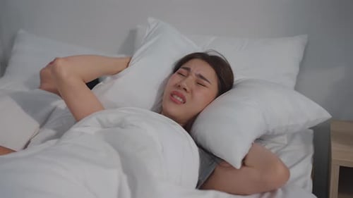 Une belle femme asiatique se sent frustrée par le fait que son mari ronfle pendant son sommeil.