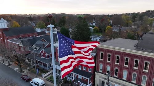 American Flag Waving Over Suburban Town at Dusk
