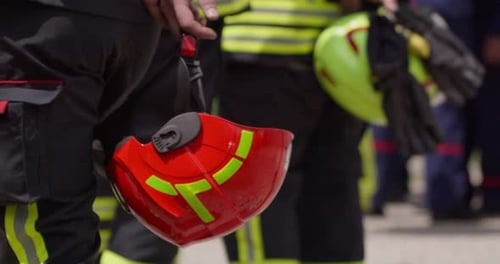 Eine Nahaufnahme konzentriert sich auf die Hand eines Feuerwehrmanns, während er einen Schutzhelm hält, der seine