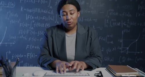 Portrait of Young Woman Science Teacher Speaking and Pointing at Chalkboard with Formula Teaching
