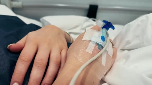 Closeup of an Intravenous Drip in the Hand of a Patient Lies on Bed in the Hospital