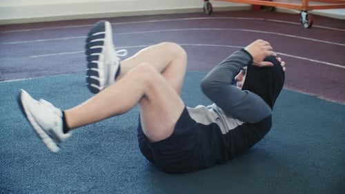 Sporty Man Doing Abs Abdominal Diagonal Crunches Training in Gym Lying on Floor