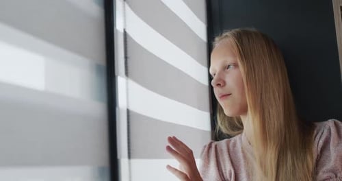 Teenage Girl Sitting on the Windowsill Looking Out the Window