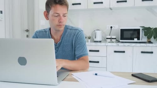 Man Works at Laptop in Bright Kitchen