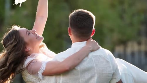 Groom Spins with a Happy Bride on His Hands Newlyweds Couple Have Fun on Warm Summer Evening Wedding