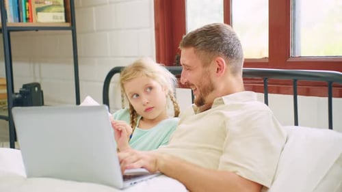 Atractivo padre caucásico usando una computadora portátil con su hija pequeña.