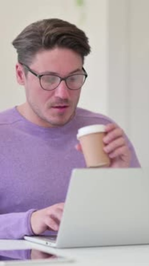 Mann mittleren Alters trinkt Kaffee bei der Arbeit, vertikales Video
