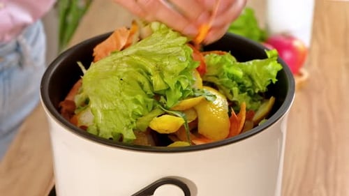 Woman recycling organic waste by composting vegetables peels in the Bokashi in the kitchen