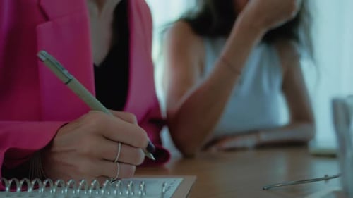 Woman Writing in Notebook During Meeting
