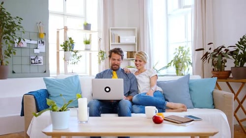 Couple Relaxing on Sofa with Laptop Indoors