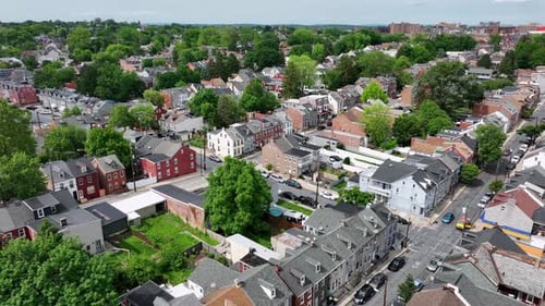 Charming american city neighborhood with row of houses and green trees. Descend drone wide shot. Sun