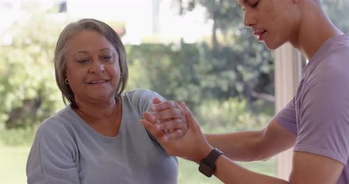 Young Adult Assists Senior Woman Stretching Her Arms