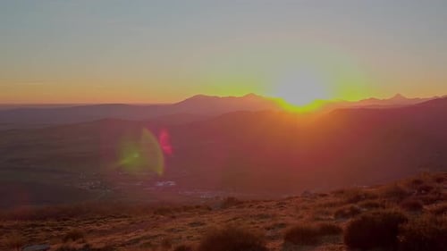 Sunset in the mountains with little town in a valley