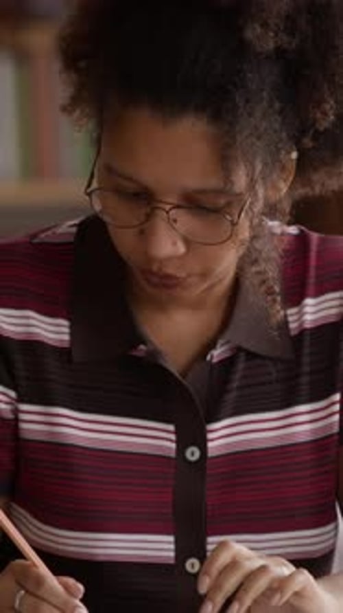 Vertical of Young Woman Doing Paperwork with Pen and Calculator at Home