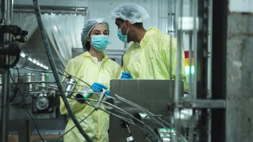 Deux ouvriers de l'industrie inspectent et contrôlent la bande transporteuse de l'usine.