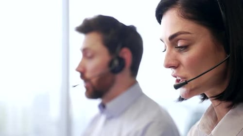 Close up of head of smiling female customer service representatives with headsets working in modern