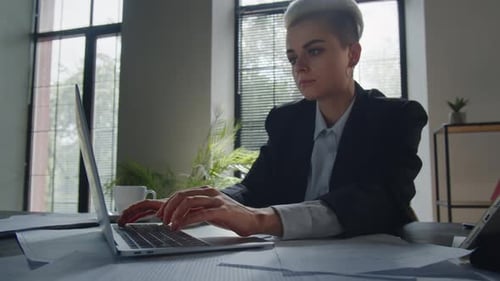 Busy Woman Reading Documents and Drinking Coffee Near Laptop in Office Beautiful Businesswoman Wear