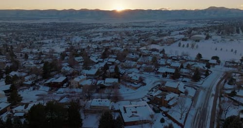 Drone shot of the sun setting over the Rocky Mountains in Denver, CO on a snowy winter day.