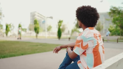 man sitting relaxed on park bench looking around