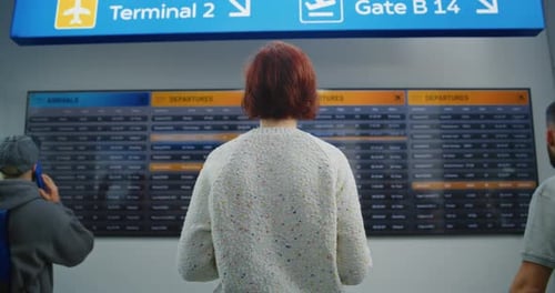 Airport Terminal Back View of Woman Checking Departure on Digital Flight Information Display