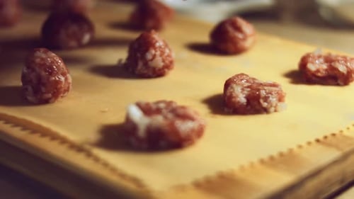 Hands Forming Meatballs on Wooden Cutting Board
