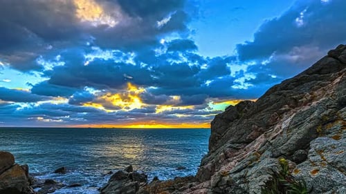Sunset on the horizon of across the fjord as seen from the rocky shoreline - dynamic sliding motion
