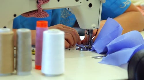 Female weaver working on industrial sewing machine in textile factory