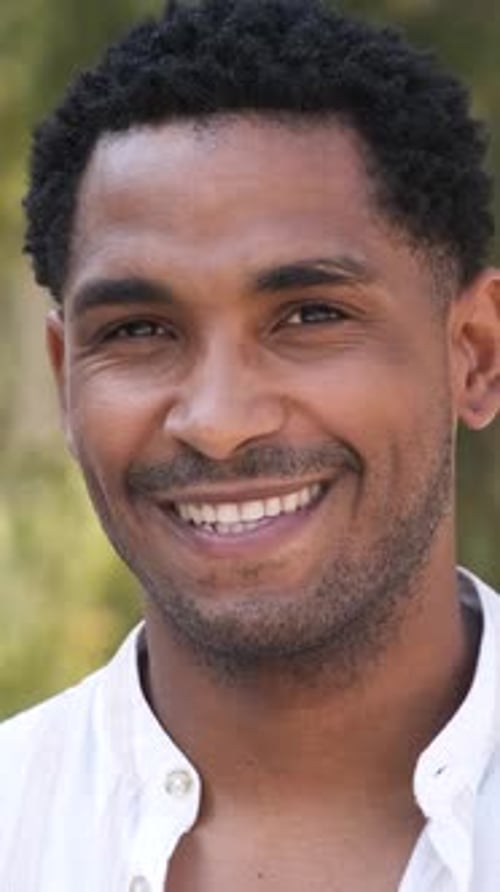 Nahaufnahme eines glücklichen jungen Mannes, der tagsüber in die Kamera schaut