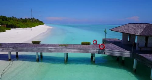 Close up aerial drift of dock on secluded Maldives island. White beach and turquoise water vanishing