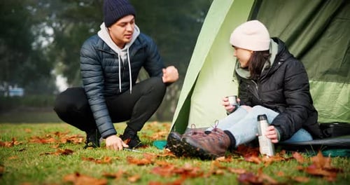 Young Couple Camping in Nature Setting up Tent