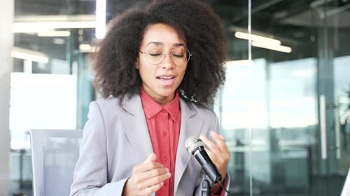 Webcam-Ansicht. Junge afroamerikanische Geschäftsfrau mit Mikrofon nimmt einen Podcast
auf und schaut