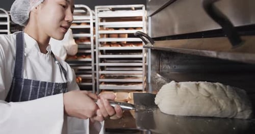Verschiedene Bäcker arbeiten in der Backküche und legen Brot in Zeitlupe in den Ofen