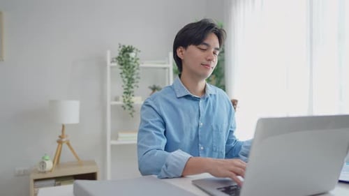 Young Man Typing on Laptop at Bright Desk