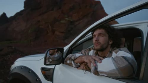 Portrait of Pensive Young Man Looking out of Car Window in Desert
