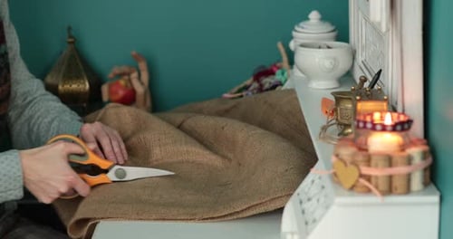 Woman cutting burlap material with scissors indoors