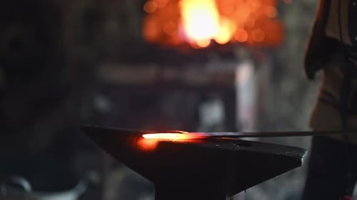 A Viking Blacksmith with a White Beard and Braided Hair Works Intently at a Forge Hammering Glowing