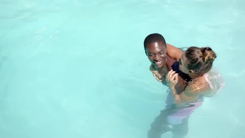 Enjoying summer vacation, happy diverse couple swimming in pool together, copy space